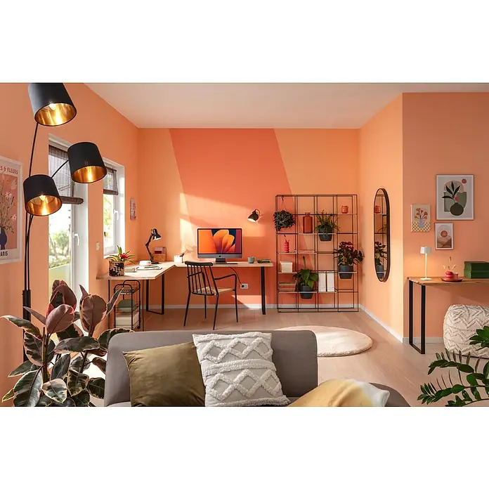 Kissen Finja - Military Olive, 45 x 45 cm, 100 % Polyester - Das Bild zeigt ein modernes Wohnzimmer mit orangefarbenen Wänden, einem Schreibtisch mit iMac, einem Bücherregal und einer Stehlampe.