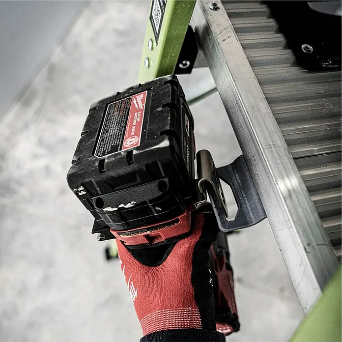 Little Giant Stehleiter MIGHTYLITE 2 Stufen - Anzahl Tritte: 2 Stk., Arbeitshöhe: 280 cm, Belastbarkeit: 150 kg, Verbundwerkstoff - Nahaufnahme eines Milwaukee-Akkus, der an einer Leiter befestigt ist, und ein Paar roter Arbeitshandschuhe sind sichtbar.