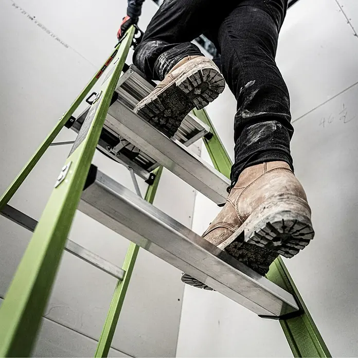 Little Giant Stehleiter MIGHTYLITE 2 Stufen - Anzahl Tritte: 2 Stk., Arbeitshöhe: 280 cm, Belastbarkeit: 150 kg, Verbundwerkstoff - Eine Leiter mit einer Person, die mit Arbeitsstiefeln die Stufen hochsteigt, vor einer weißen Wand.