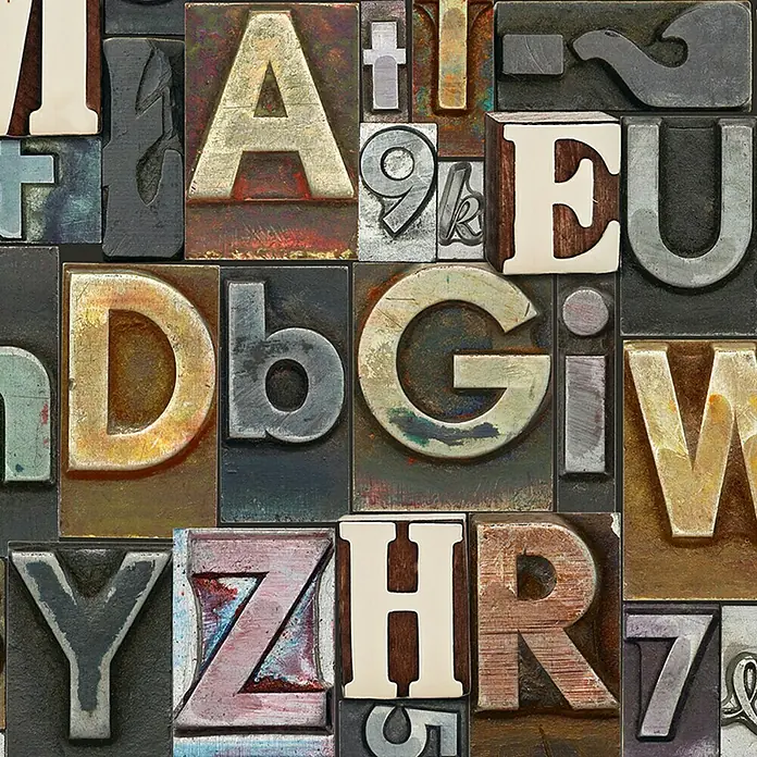A.S. Création Designpanel pop.up - Buchstaben, Bunt, 35 cm x 2,5 m - Eine Nahaufnahme von verschiedenen alten Druckbuchstaben, die ein nostalgisches und künstlerisches Muster bilden.