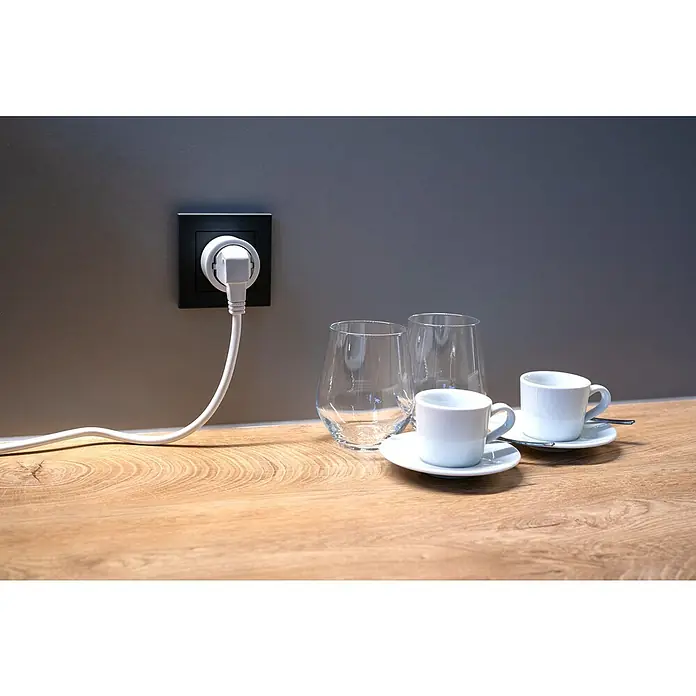 Intertek Funksteckdosen-Set mit Fernbedienung - Weiß, 3 Stk. - Ein Stecker in einer Steckdose neben Gläsern und Tassen auf einem Holztisch, minimalistisch und modern.