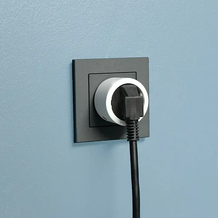 Intertek Funksteckdosen-Set mit Fernbedienung - Weiß, 3 Stk. - Schwarzer Stecker mit weißem Smart-Zwischenstecker in grauer Steckdose an blauer Wand. Intelligente Haustechnik für den Haushalt.