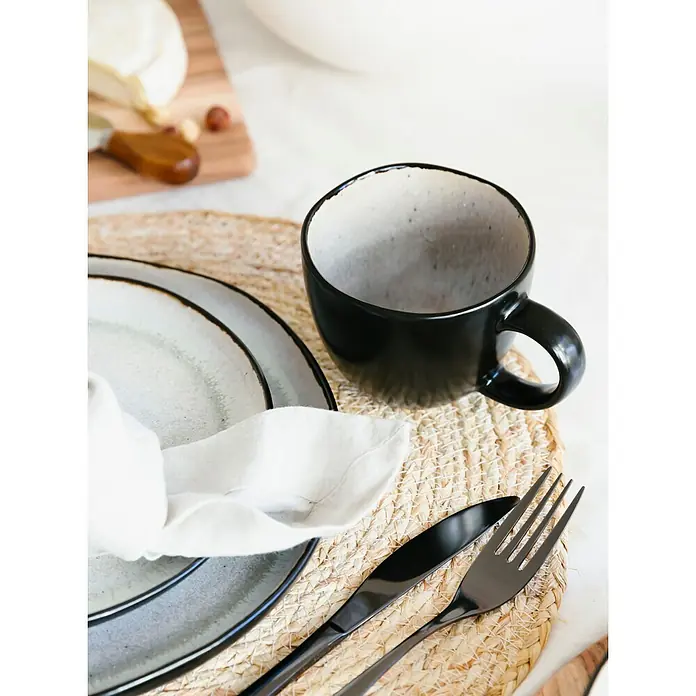 Tasse Lunar - Ø x H: 14 x 9 cm - Nahaufnahme von Geschirr, einschließlich einer schwarzen Tasse, Tellern und Besteck, auf einem Tisch mit einer natürlichen Tischdecke.