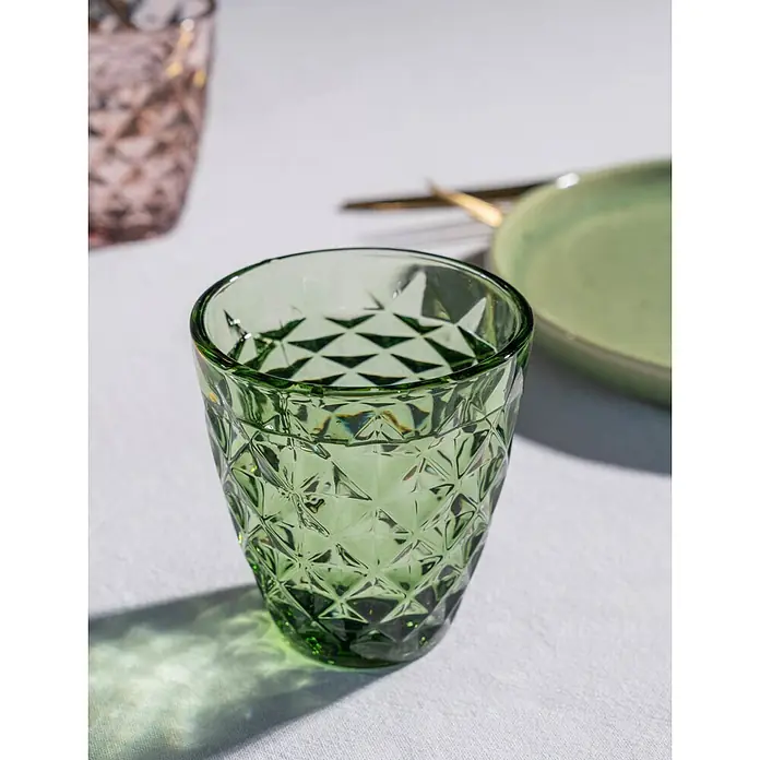 Trinkglas Prisma - 4 Stk., Fassungsvermögen: 0,22 l, Grün - Nahaufnahme eines grünen Vintage-Trinkglases mit Rautendesign, das auf einer weißen Tischdecke steht, mit weichem, natürlichem Licht.