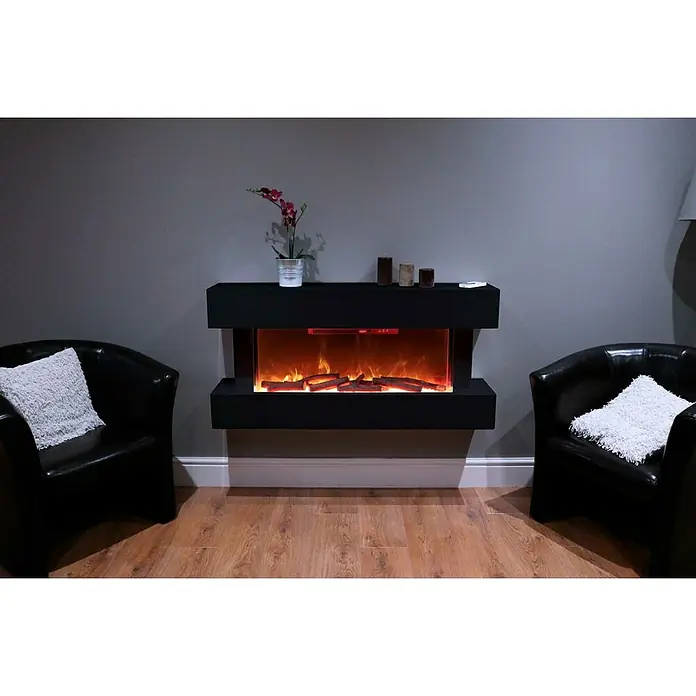 Focalpoint Chimenea eléctrica Ashford Wall Suite - Negro, 2.000 W, 26,5 x 122 x 60 cm - Una chimenea eléctrica con llamas simuladas está situada entre dos sillones negros con cojines blancos en una sala de estar acogedora.