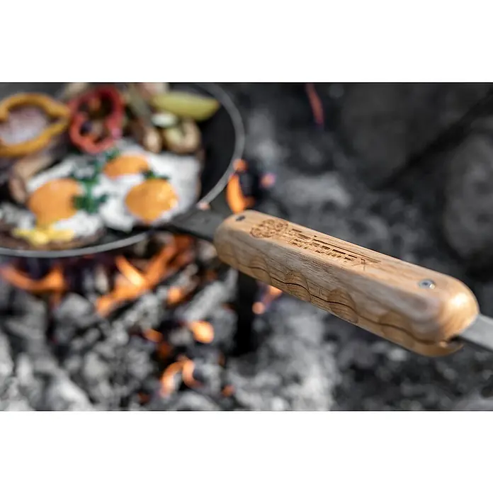 Petromax Haltegriff - L x B x H: 16 x 3,9 x 1,4 cm, Holz - Pfanne mit Eiern und Gemüse über dem Lagerfeuer, der Holzgriff der Pfanne ist gut sichtbar.