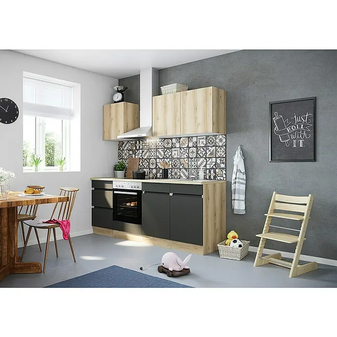 Optifit Singleküche Kaya/Noah - Breite: 210 cm, Wildeiche Nachbildung / Anthrazit, Farbe Dunstabzugshaube: Silber - Küchenansicht mit modernen Schränken in Holzoptik und matten, schwarzen Fronten. Ein heller Raum mit Esstisch und Kinderstuhl ergänzt das Bild.
