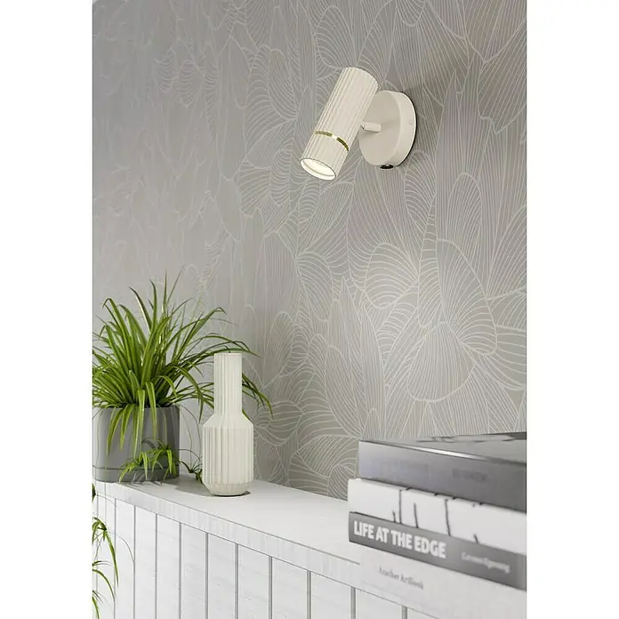Eglo Caminia Aplique de pared LED - 5 W, Arena/Oro - Primer plano de una lámpara de pared moderna y giratoria en blanco con detalles dorados sobre una pared gris con un estampado de hojas.