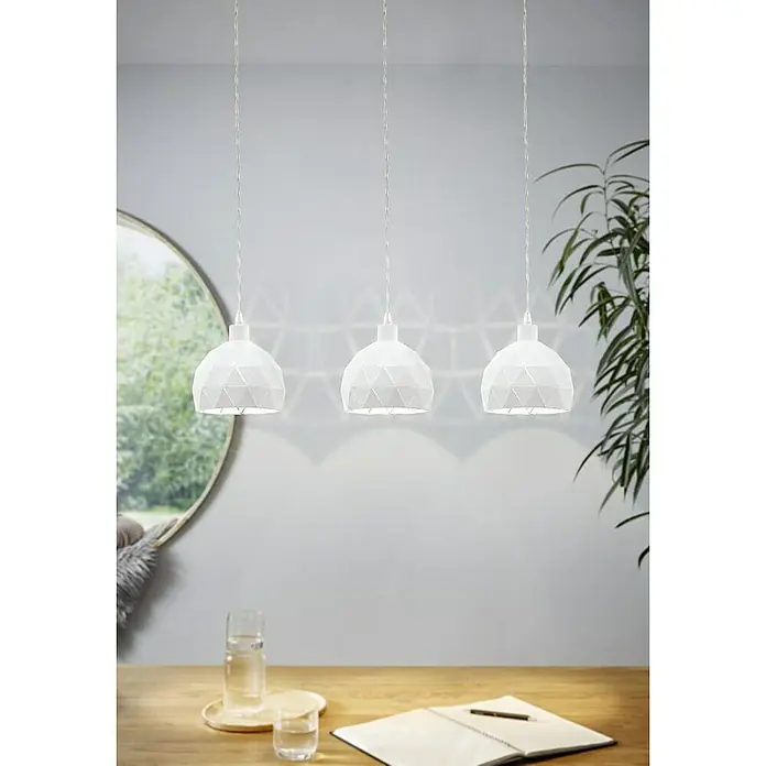 Eglo Roccaforte Lámpara colgante redonda - 40 W, L x An x Al: 45 x 17 x 110 cm, Blanco, E14 - Esta foto presenta tres lámparas colgantes blancas con patrones geométricos, colgadas sobre una mesa de madera con vaso y cuaderno.