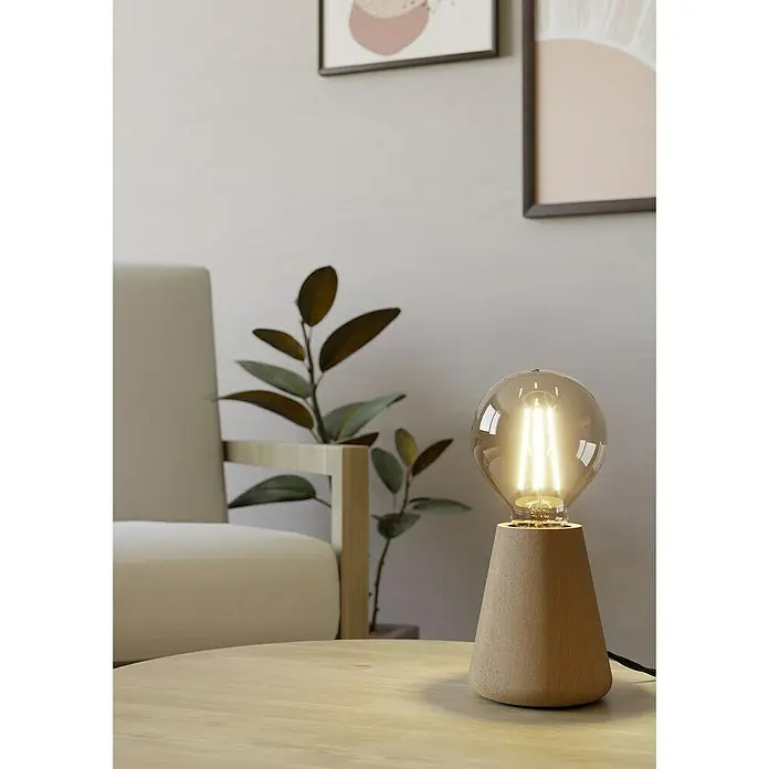 Eglo Lámpara de sobremesa Asby - 40 W, Beige, E27 - Primer plano de una lámpara de mesa con bombilla decorativa sobre mesa de madera, con silla y plantas al fondo.