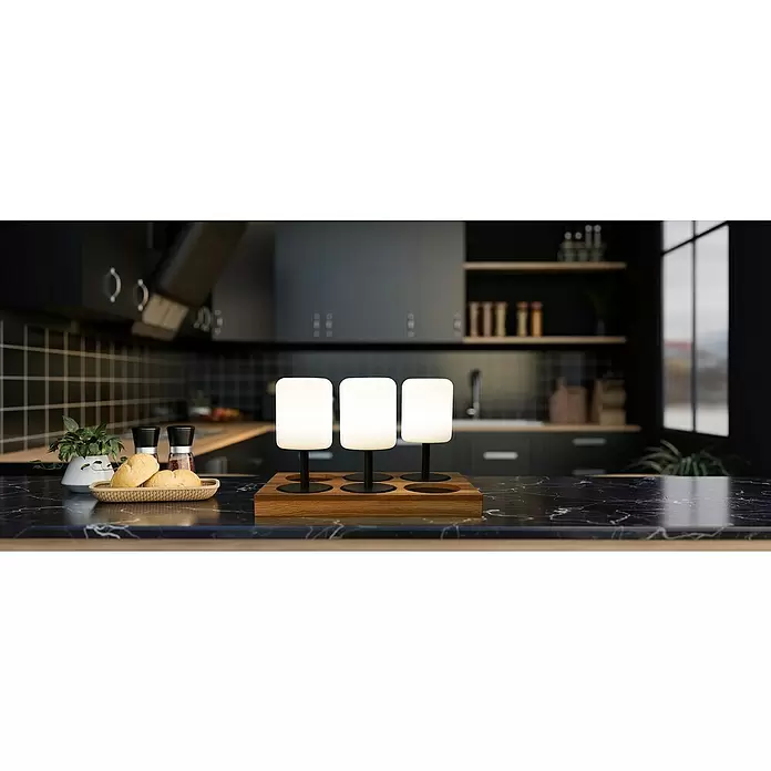 FHL easy Ladestation Super Charger - 6 Ladeplätze, L x B x H: 44,7 x 26,7 x 3,3 cm - Drei weiße, tragbare Lampen mit schwarzen Füßen auf einer Holzladestation, auf einer Küchentheke.