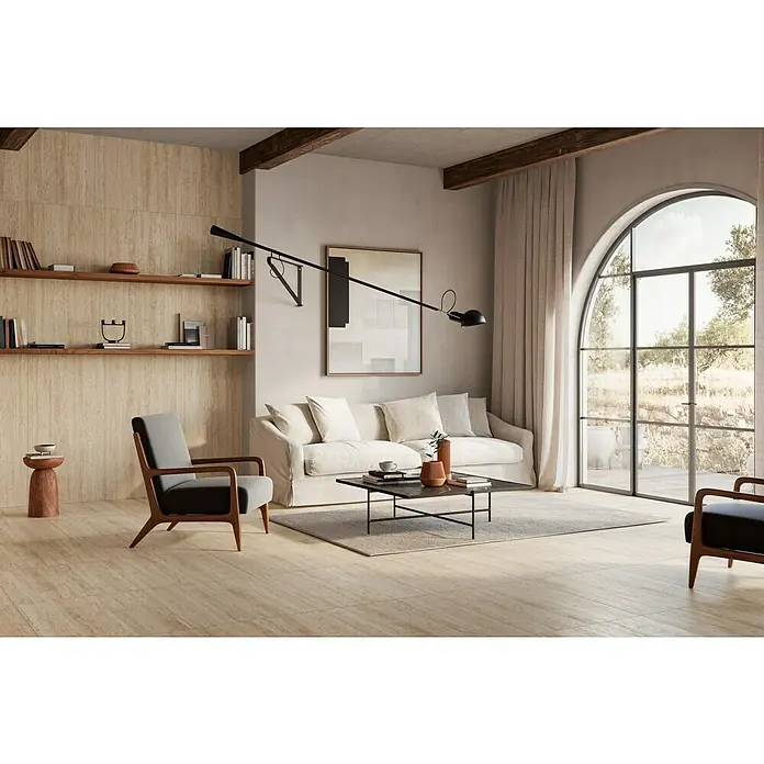Atlas Concorde Solution Feinsteinzeugfliese Pompei Aureo Classic - 60 x 60 cm, Hellbraun, Matt - Elegantes Wohnzimmer mit beigen Fliesen, Regalen und einer modernen Lampe, das eine stilvolle und einladende Atmosphäre schafft.\n