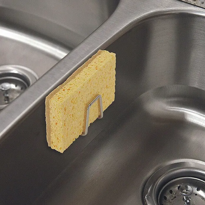 Soporte de esponja - Acero inoxidable, 1 ud. - Esponja amarilla en un soporte plateado en el fregadero. La esponja es ideal para limpiar platos y superficies.