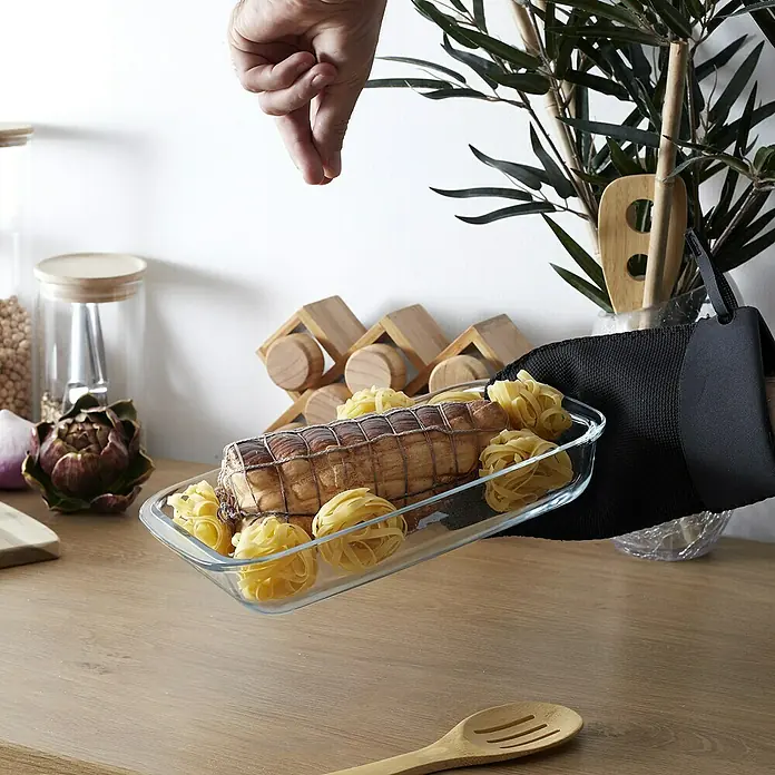 Manopla de neopreno - Goma, Negro/Burdeus, Negro/Gris, Negro/Beige - Un asado en una fuente de vidrio se sazona con pasta, mostrado sobre una encimera de cocina de madera, sujetado con un guante de horno.