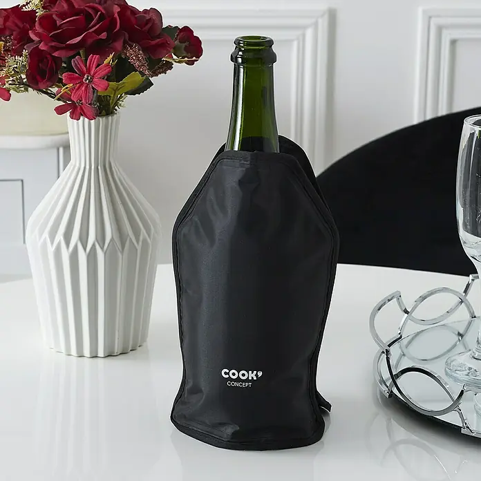 Funda de botella - Negro, 15,5 x 2 cm, Específico para: Mantener frías las botellas - Una botella de vino verde está dentro de un enfriador de botellas negro de Cook Concept, que está sobre una mesa junto a un jarrón y vasos.