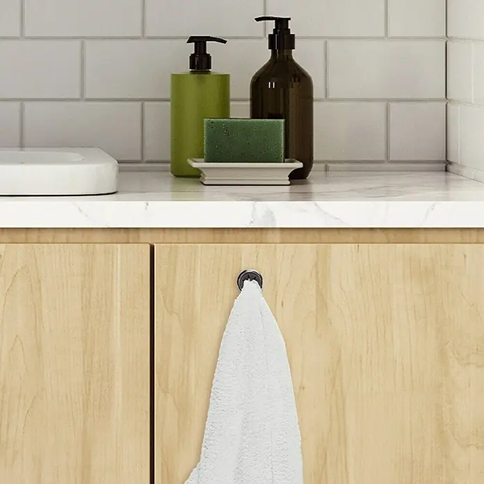 Colgador de trapos de cocina - Cromo - Una toalla blanca cuelga de un gancho redondo de color plateado en una puerta de madera clara en el baño, añadiendo un toque elegante.