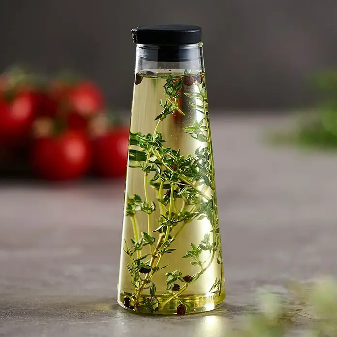 Aceitera y vinagrera - 280 ml, Vidrio - Esta imagen muestra una botella de vidrio decorativa llena de hierbas y aceite. Las hierbas y el aceite crean una composición visual estéticamente agradable.