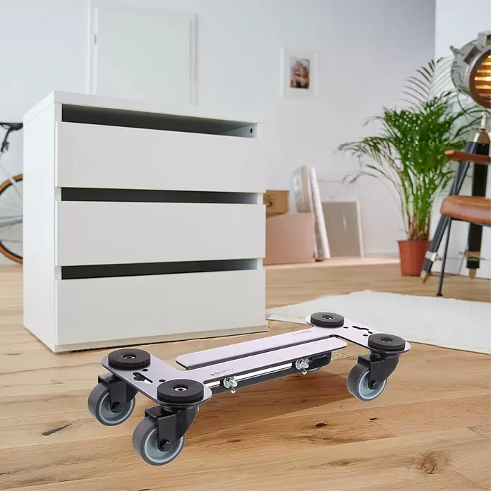 Wagner System Transportroller MM 4120 - L x B x H: 35 x 16,5 x 9 cm, Traglast: 250 kg, Stahl - Silberner Möbelroller mit schwarzen Rädern und Pads, auf Holzboden neben einer weißen Kommode platziert.