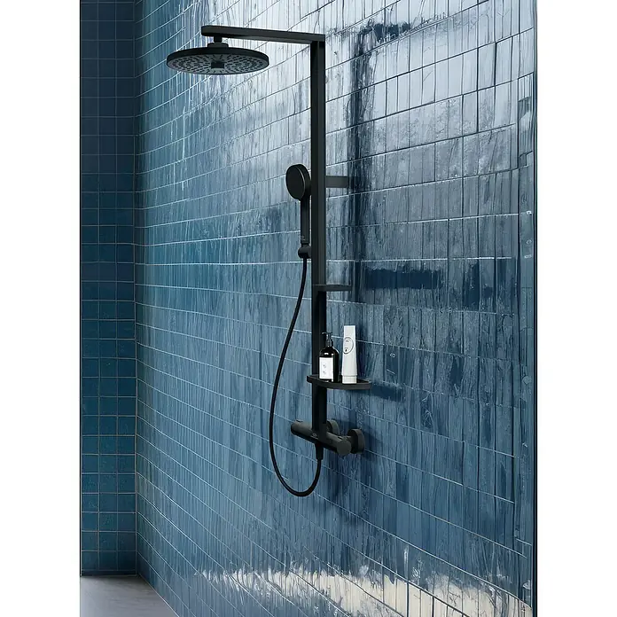Ideal Standard Überkopfbrausen-Set Alu+Schwarz, Durchmesser Kopfbrause: 26 cm - Duschsystem in Schwarz mit Kopf- und Handbrause, Ablage für Pflegeprodukte vor blauem Fliesenmuster.
