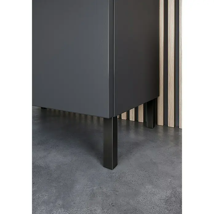 Germania Arcena Waschtischunterschrank - B x T x H: 60 x 34 x 56 cm, Graphit, Matt - Nahaufnahme eines modernen, grauen Schranks mit schlanken, schwarzen Metallbeinen auf einem grauen Betonboden. Elegantes und minimalistisches Design.