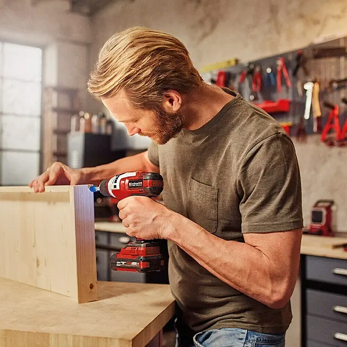 Einhell Power X-Change 18V Akku-Bohrschrauber TE-CD 18 Li E-Solo - 18 V, Ohne Akku - Ein Mann arbeitet mit einem Einhell Akku-Bohrschrauber an einem Holzprojekt. Der rote Bohrschrauber ist gut sichtbar und im Fokus.