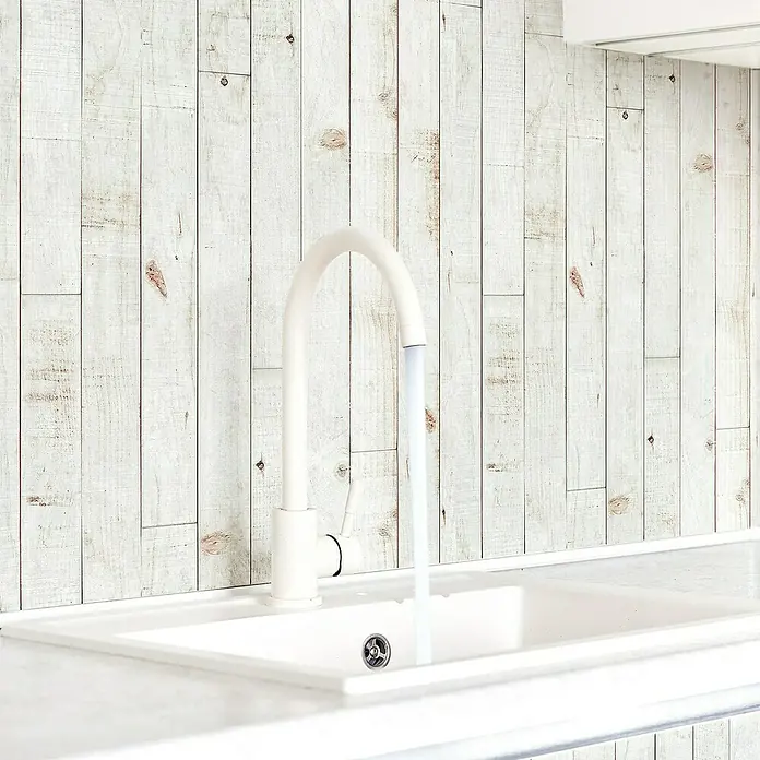 Papel pintado de vinilo autoadhesivo Madera - Blanco, L x An: 280 x 65 cm - Primer plano de un fregadero de cocina blanco y moderno con grifo y agua corriente, con un fondo de paneles de madera.