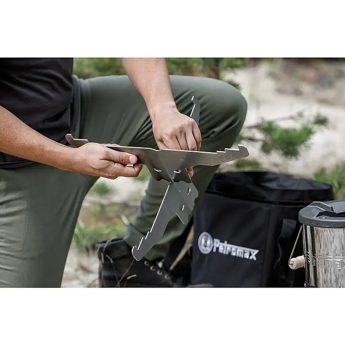 Petromax Grillplatte - Durchmesser: 27,5 cm, Passend für: Petromax Raketenofen - Eine Person montiert einen Petromax Feuerstand, ein tragbares Kochgerät für Outdoor-Abenteuer. Ideal für Camping und Bushcraft.