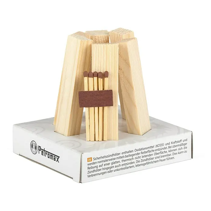 Petromax Anzünder Feuerkit - Holz - Nahaufnahme von Petromax Sturmhölzer mit Reibefläche und Zündhölzern in einer dekorativen Holzscheit-Halterung auf einer weißen Schachtel.