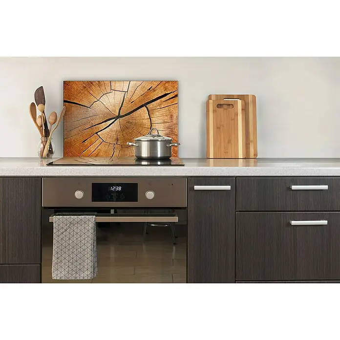 CUCINE Küchenrückwand - Circled Wood, 60 x 40 cm, Stärke: 6 mm, Einscheibensicherheitsglas (ESG) - Nahaufnahme eines Küchenrückwandbildes mit Holzmaserung über dem Herd, ergänzt durch Kochutensilien und Schneidebretter.