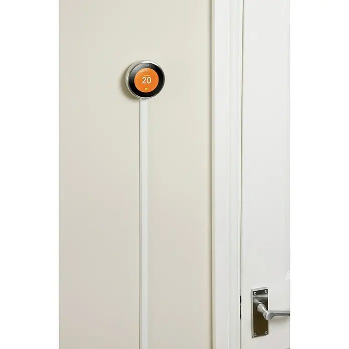 D-Line Kabelkanal Halbrund - 1 m, 20 x 10 mm, Weiß - Ein intelligenter Nest-Thermostat mit weißem Kabel ist an einer Wand neben einer Tür montiert. Der Thermostat zeigt eine Temperatur von 20 Grad an.