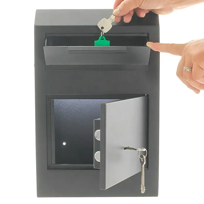 Rottner Einwurftresor Cashmatic - 11,5 x 25 x 38 cm, Doppelbartschloss - Das Bild zeigt einen grauen Schlüsselsafe mit zwei Fächern, in den gerade ein Schlüssel mit Anhänger eingeworfen wird.