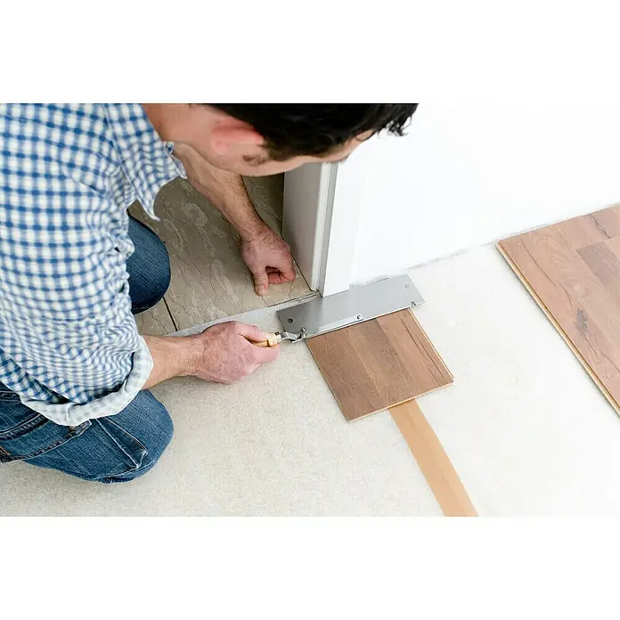 Wolfcraft Sierra de mano 6925000 - Largo: 39 cm - Un manitas utiliza una sierra especial para recortar un elemento del marco de la puerta para la instalación de laminado. La herramienta asegura cortes precisos.