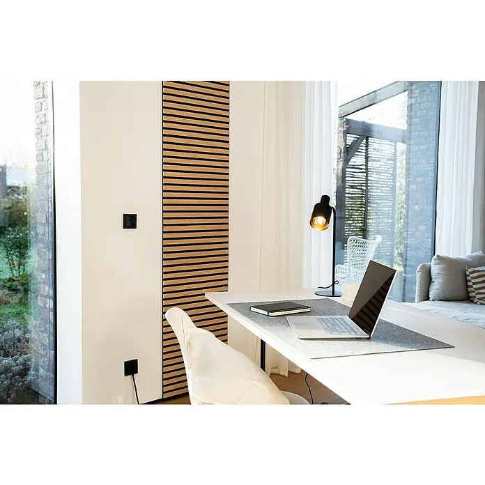 Jangal Akustikpaneel Modular Wall Furnier - Fanal Oak, 520 x 520 x 10 mm - Ein heller Arbeitsplatz mit einem modernen Laptop, einer Lampe und einem Notizbuch auf einem weißen Schreibtisch. Die Wandpaneele aus Holz verleihen Wärme.