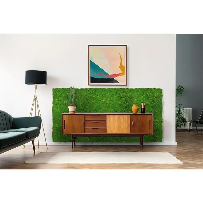 Jangal Wandpaneel Modular Wall Design Moos - Light Green Fibre, 520 x 520 mm - Wohnzimmer-Interieur mit Sideboard vor grüner Mooswand, darüber ein abstraktes Gemälde. Eine Stehlampe und ein Sofa ergänzen die Einrichtung.