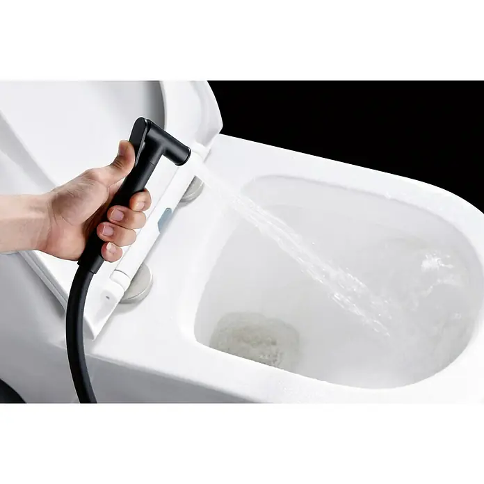 Camargue Natur Ducha higiénica inodoro - Negro - Primer plano de un pulverizador de bidé de mano con manguera rociando agua en una taza de inodoro.