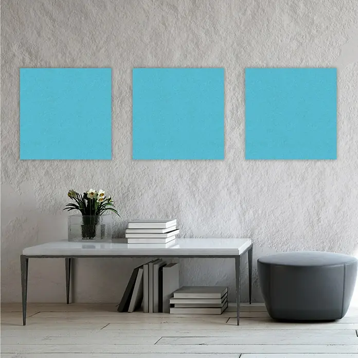 Jangal Wandpaneel Modular Wall PET Filz - Blue, 520 x 520 x 6 mm - Drei türkisfarbene Leinwandbilder an einer Wand über einem Tisch mit Dekor, die das minimalistische Design hervorheben.