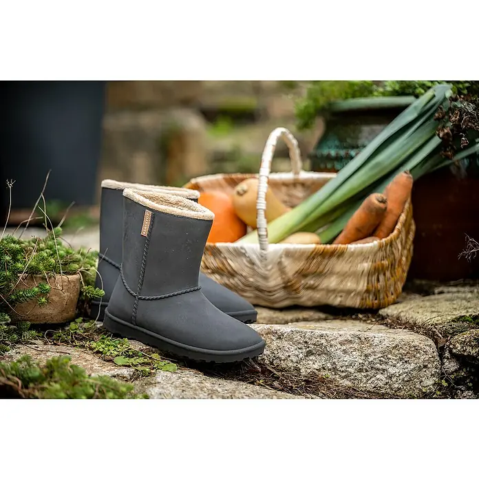 Black Fox Winterstiefel Cheyennetoo - Schuhgröße: 42, Schwarz - Ein Paar graue Blackfox-Stiefel stehen auf Steinen, umgeben von Grünpflanzen und einem Korb mit Gemüse.