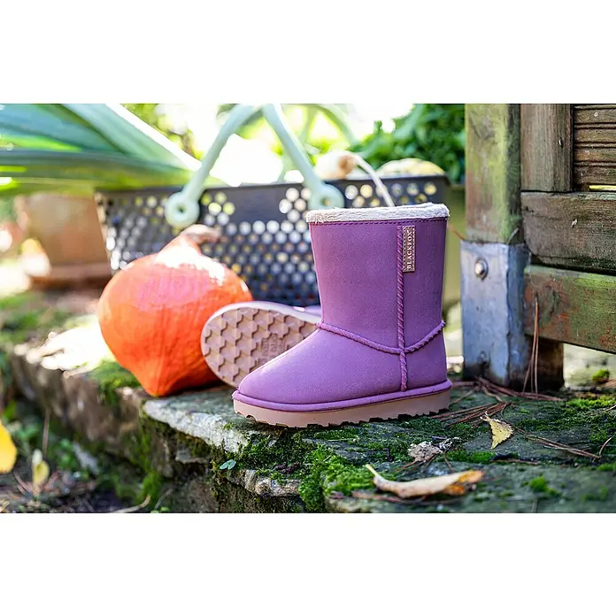Black Fox Winterstiefel Cheyennetoo - Schuhgröße: 24, Himbeere - Nahaufnahme von lilafarbenen BLACKFOX-Stiefeln vor einem orangefarbenen Kürbis und einem grünen Hintergrund.