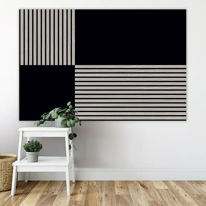 Jangal Wandpaneel Modular Wall PET Filz - Black, 520 x 520 x 6 mm - Wandbild mit Holz- und Schwarz-Quadraten über einem Hocker mit Pflanzen.