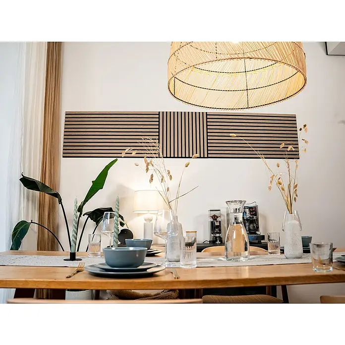 Jangal Akustikpaneel Modular Wall Furnier - Davert Oak, 520 x 520 x 10 mm - Stilvolle Wandpaneele aus Holz mit horizontalen und vertikalen Streifen über einem gedeckten Esstisch.