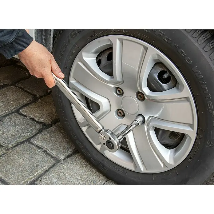 UniTEC Drehmomentschlüssel - ½″ Vierkant, Einstellungsbereich: 42 Nm - 210 Nm - Ein Mann benutzt einen Drehmomentschlüssel, um eine Radmutter an einem Reifen festzuziehen, wobei der Fokus auf dem Werkzeug und dem silbernen Rad liegt.