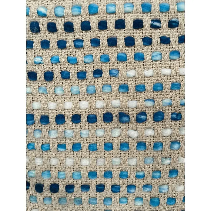 Cojín Dakira - 45 x 45 cm, Textil, Azul, Cuadrado - Primer plano de una alfombra tejida con detalles azules, turquesas y blancos sobre un fondo beige, mostrando textura y patrón.