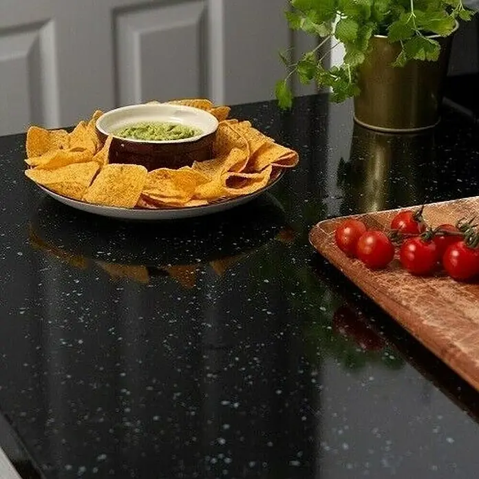 D-c-fix Dekorfolie Black Granit - 67,5 x 200 cm, Black Granit, Schwarz - Bild einer Schale mit Tortilla-Chips und Guacamole, zusammen mit Tomaten auf einem Servierbrett, alles auf einer schwarzen Theke.