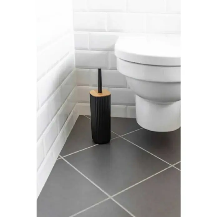 Wenko Rotello WC-Bürstengarnitur - Kunststoff, Schwarz/Natur - Eine moderne Badezimmer-Szene mit einer schwarzen Toilettenbürste neben einer weißen Toilette und grauen Bodenfliesen.