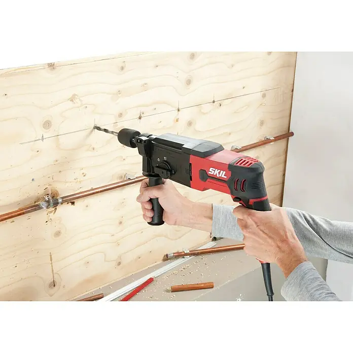 Skil Kombihammer 1770 GA - 850 W, 2,8 J, SDS-Plus-Aufnahme - Aufnahme einer roten SKIL-Bohrmaschine bei der Arbeit, ideal für Heimwerkerprojekte und Bauarbeiten.