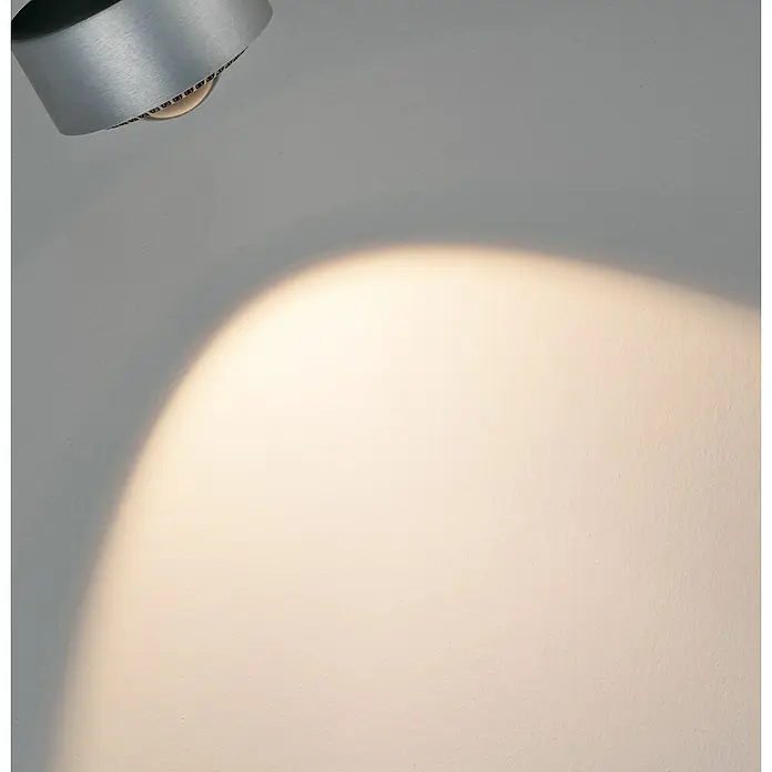 Paulmann URail LED-Spot Aldan - Chrom matt, Tageslichtweiß, Ø x H: 9,9 x 17,9 cm - Nahaufnahme einer modernen, silbernen Lichtquelle, die ein warmes Licht auf eine weiße Wand wirft und eine stimmungsvolle Atmosphäre erzeugt.
