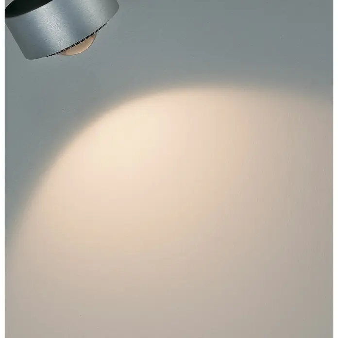 Paulmann URail LED-Spot Aldan - Chrom matt, Tageslichtweiß, Ø x H: 9,9 x 17,9 cm - Nahaufnahme einer modernen Deckenleuchte, die ein warmes Licht auf eine Wand wirft. Die Leuchte ist silberfarben und hat ein schlichtes Design.