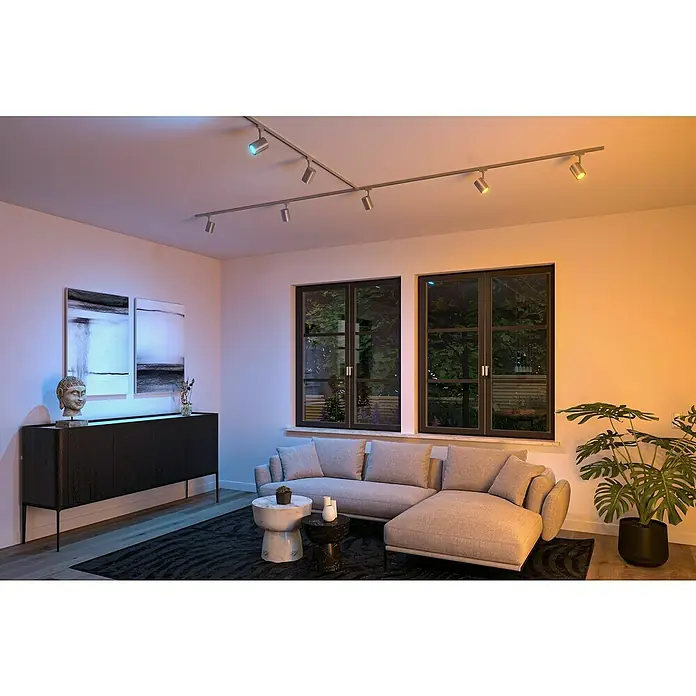 Paulmann URail LED-Spot Luxe - 10 W, Chrom matt, 6,5 x 9 x 16,3 cm, RGBW - Das Bild zeigt eine moderne Wohnzimmerbeleuchtung mit einer auffälligen, verstellbaren Deckenleuchte mit mehreren Strahlern für flexibles Licht.
