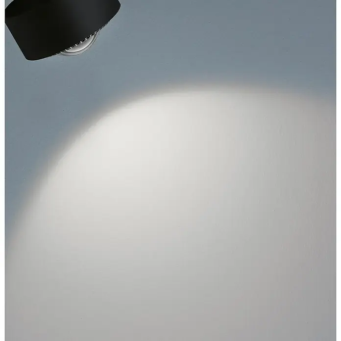 Paulmann URail LED-Spot Aldan - Schwarz matt, Neutralweiß, Ø x H: 9,8 x 17 cm - Nahaufnahme einer modernen schwarzen Deckenleuchte, die ein helles Licht auf eine weiße Wand wirft. Elegantes Design trifft auf funktionale Beleuchtung.