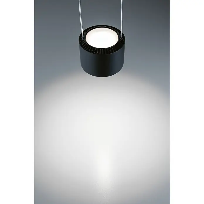 Paulmann URail LED-Pendelleuchte Aldan - Neutralweiß, Schwarz matt, Ø x H: 10 x 150 cm, 4.000 K - Nahaufnahme einer schwarzen zylindrischen Pendelleuchte mit weißem Licht, die von zwei dünnen Kabeln an einer grauen Decke hängt.